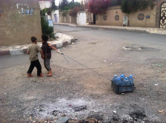 Children struggle to pull the heavy water cans