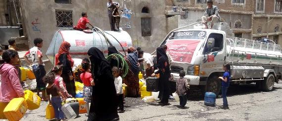 Women and children filling containers from water tanks