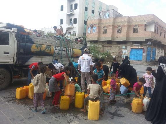 Women and children filling water jugs from water distribution truck