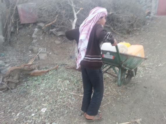 A boy transporting merchandise in wheel barrow