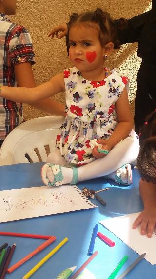 A young orphaned girl enjoying face painting and crafts