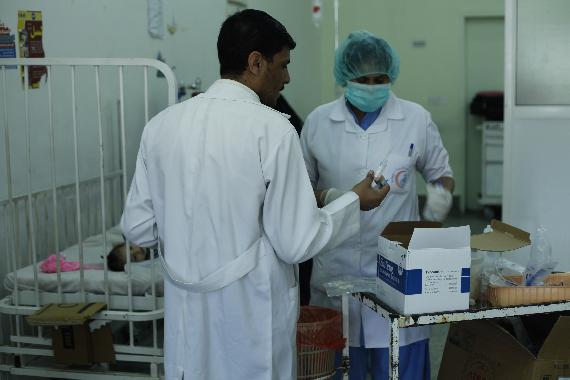 Two doctors inspect a box of disposable syringes in the Emergency Department in Al-Sabeen Maternity and Child Hospital (Photographer: Yasser Mohammed Rayes)