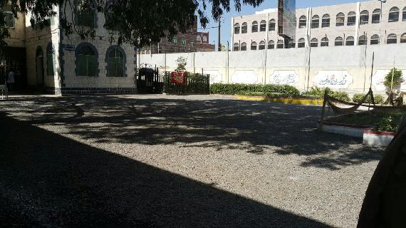Black gravel yard in front of male ward at Al-Amal Hospital
